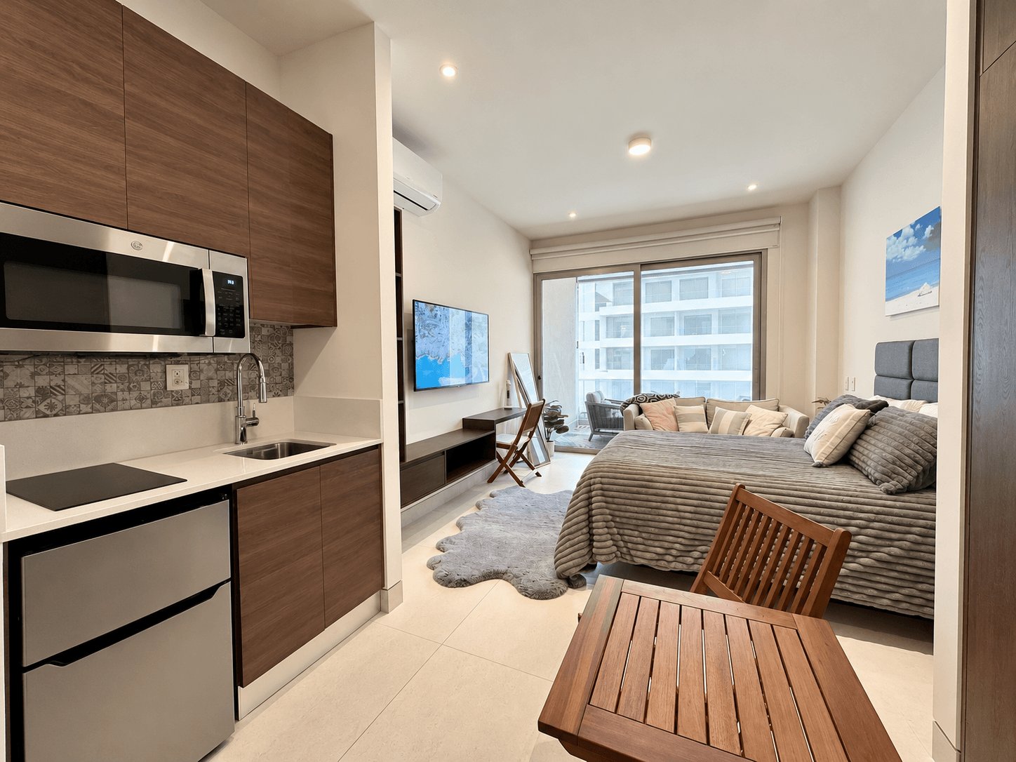 Studio with integrated kitchenette, seating area, and balcony access.