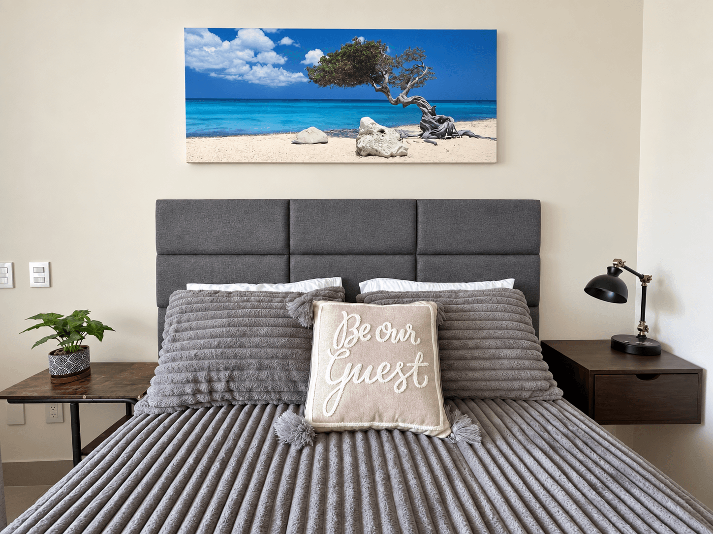 Bed with upholstered headboard and coastal-themed wall art.